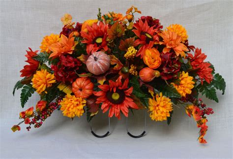 An Arrangement Of Flowers And Pumpkins Is Displayed On A White