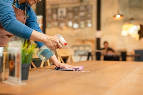 Premium Photo Waiter Cleaning The Table With Spray Disinfectant On