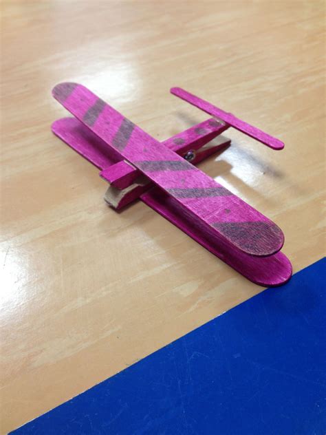 A Pink Toy Airplane Sitting On Top Of A Wooden Table Next To A Blue Strip