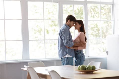 Satisfied Cheerful Young Husband And Wife Dancing And Hugging Together In Kitchen Interior Stock