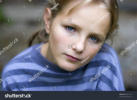 Sad Little Girl Is Looking With Serious Face At Camera Stock Photo