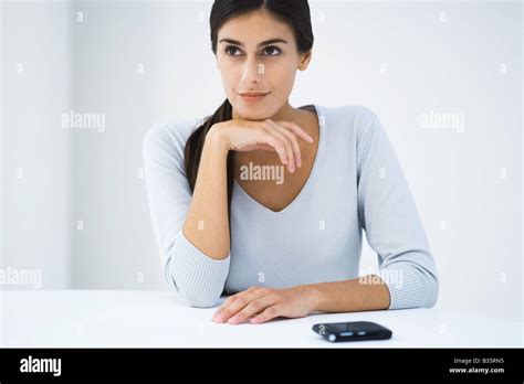 Frau Sitzt Am Tisch Mit Der Hand Unter Kinn Wegschauen Stockfotografie