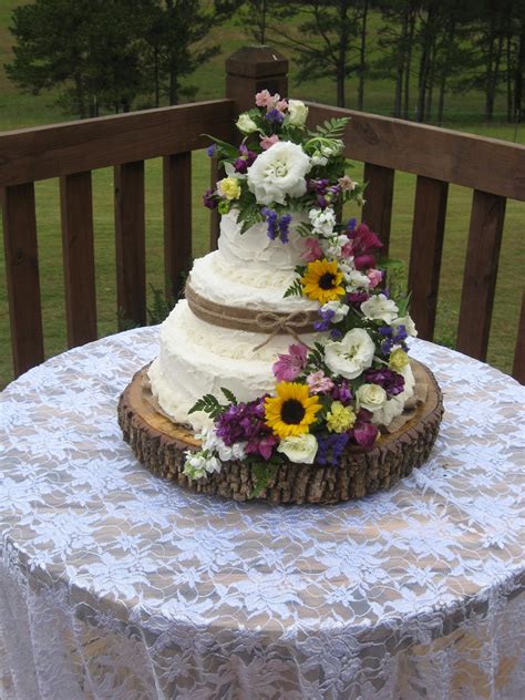 Cake Sitting On A Slice Of A Tree And Sitting A Wooden Spool With White