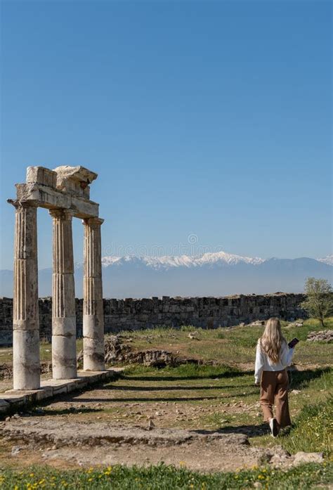 Rear View Of Woman At Roman Ruins With Snow Capped Mountain Peaks In