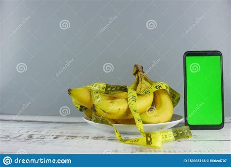 bunch  bananasmeasuring tape  smartphone  wooden background mockup  healthy eating