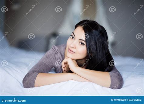 Woman In Bed Lying On Her Stomach Smiling Happy And Relaxed On A Leisure Day At Home Stock
