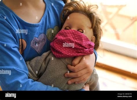 Close Up Of Little Girl Holding Doll With Mouth Protection Stock Photo