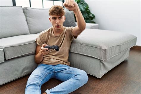 Young Caucasian Man Playing Video Game Holding Controller At Home
