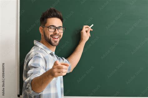Male Teacher Writing On Blackboard In Classroom Stock Photo Adobe Stock