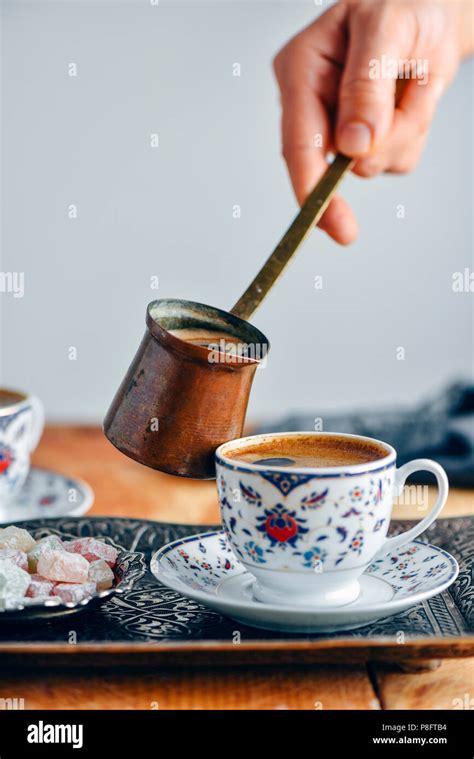 A Woman Pouring Turkish Coffee Into A Turkish Coffee Cup From A Copper
