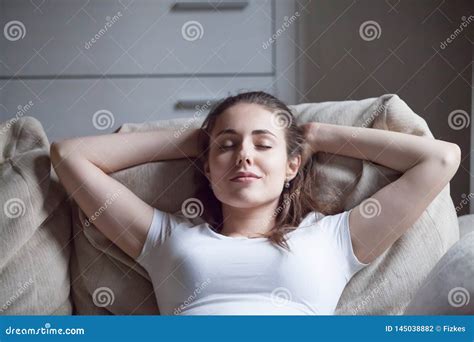 Happy Woman Relaxing On Sofa At Home With Eyes Closed Stock Photo