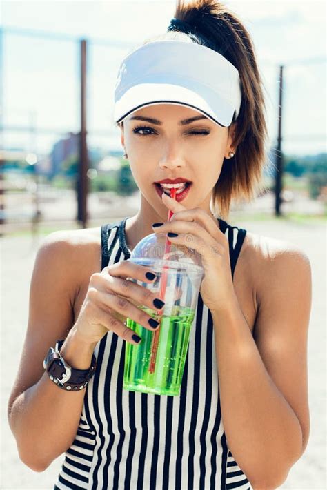 Sporty Woman Drinking Water Against The Sportsground Stock Photo