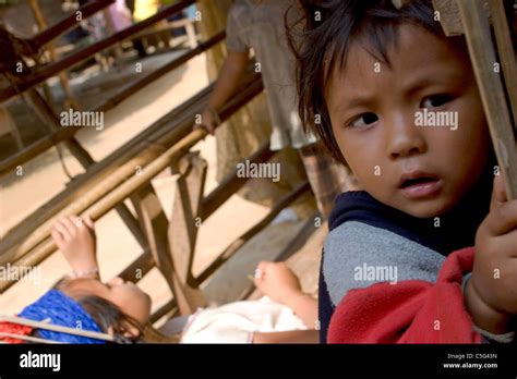 A Young Karen Paduang Refugee Girl Is Standing Outside Her Home In A