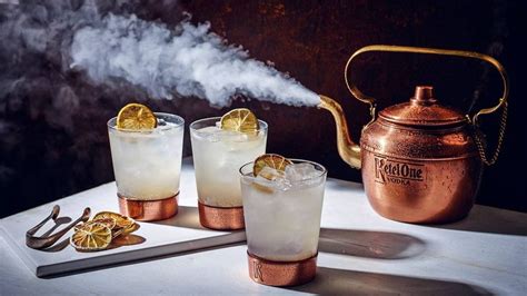 Three Glasses Filled With Ice And Lemons Next To A Copper Kettle