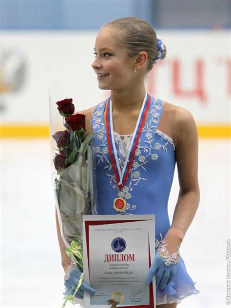 A Female Figure Skater Holding Flowers And An Award Plaque