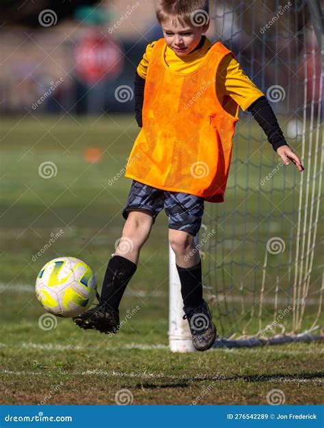 Young Boy Kicking Soccer Ball Playing Goalie In Action Shot During Game