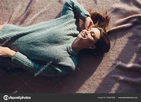 Beautiful Sexy Tan Brunette Woman Posing In Bedroom Wearing Cozy Grey Sweater And Knitted Socks