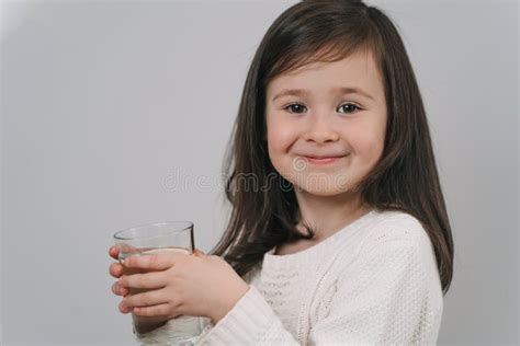 The Child Drinks Water From A Glass A Girl With Dark Hair Holds A