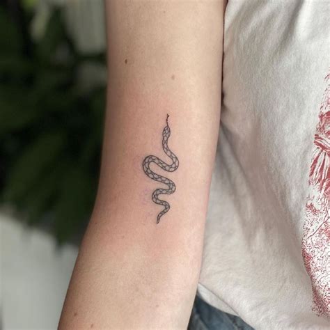 A Womans Arm With A Snake Tattoo On The Left Side Of Her Arm