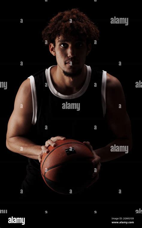 Professional Basketball Player Holding A Ball Against Black Background