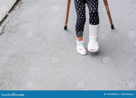 Kid With Broken Leg Is On Crutches On The Street Conceptual Photo