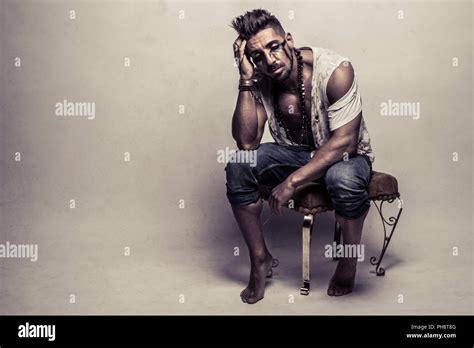Muscular Man In Ragged Clothes Sitting On A Chair Stock Photo Alamy