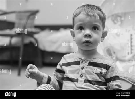 Black And White Portrait Of A Sitting Two Year Old Boy At Home Stock