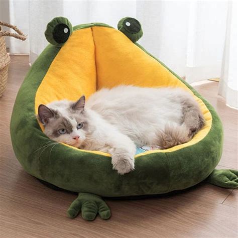 A Cat Is Laying In A Frog Shaped Bed
