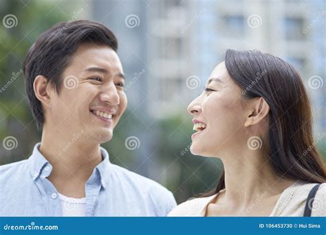 Portrait Of Young Chinese Couple Standing And Smiling Outdoor In Garden