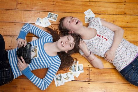 Girls Lying On Floor With Camera Surrounded By Photographs Stock
