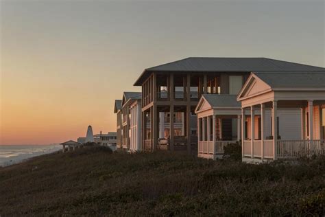 A Row Of Beach Houses Sitting On Top Of A Hill Next To The Ocean