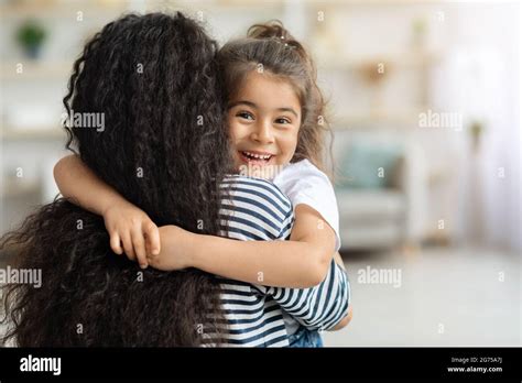 Cute Little Girl Hugging Her Mother And Cheerfully Smiling Stock Photo