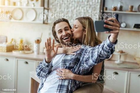 Happy Caucasian Millennial Husband With Stubble And Blonde Wife Hugs Lady Kiss On Cheek And Take