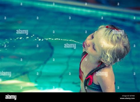 blondes mädchen im badeanzug spucken wasser im schwimmbad stockfotografie alamy