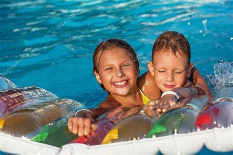 Счастливые дети играющие в голубой воде бассейна — Стоковое фото