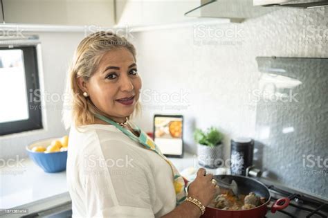 Portrait Of A Mature Latin Woman Cooking At Home Preparing Albondigas
