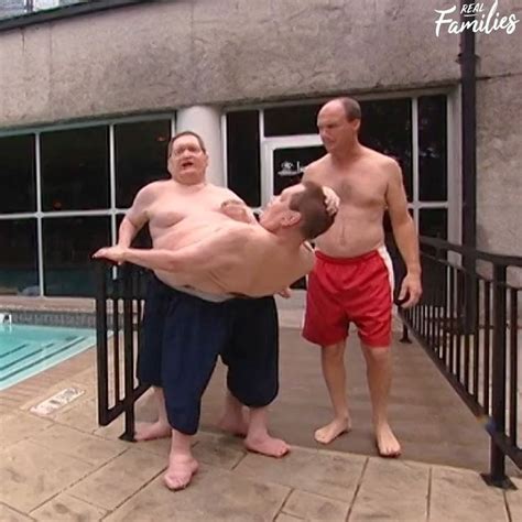 Two Men Standing Next To Each Other In Front Of A Swimming Pool With