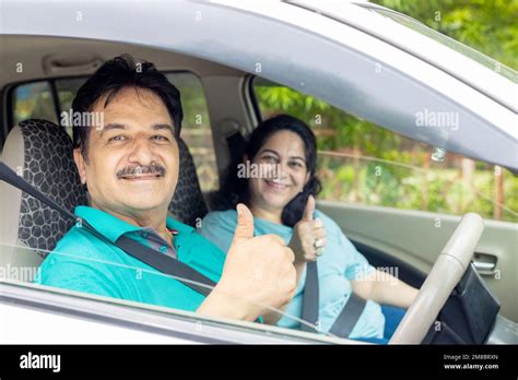 Happy Indian Mature Couple Sitting In Car Wearing Seat Belt Do Thumbs Up With Hand Ready To