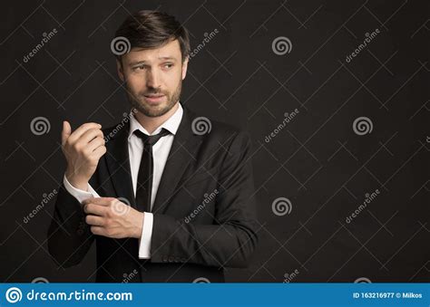 Handsome Businessman In Suit Buttoning Shirt Sleeve Standing In Studio
