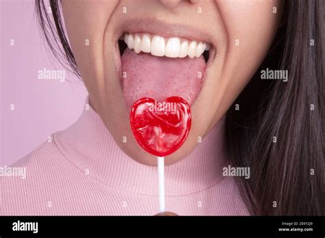 Woman S Mouth Smiling Showing Teeth And Sticking Out Her Tongue Licking A Red Heart Shaped Candy