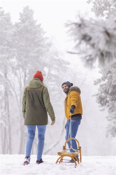 Couple Pulling Sled And Walking On Snowy Winter Day In Mountains Stock