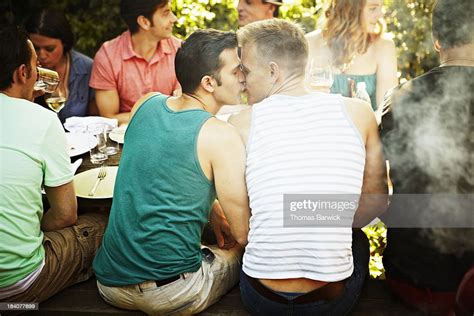 Kissing Gay Couple Sitting At Table With Friends Photo Getty Images