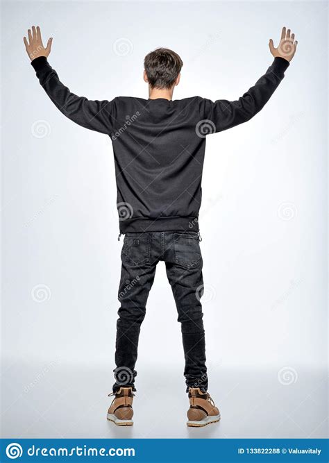 Back View Teen Boy Stands At Studio With Raised Arms Stock Photo