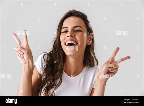 cheerful beautiful nice girl smiling and showing peace sign isolated over white background stock