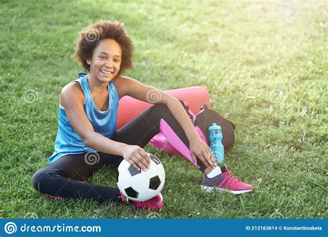 Cheerful Afro American Girl With Soccer Ball Sitting On Grass Stock