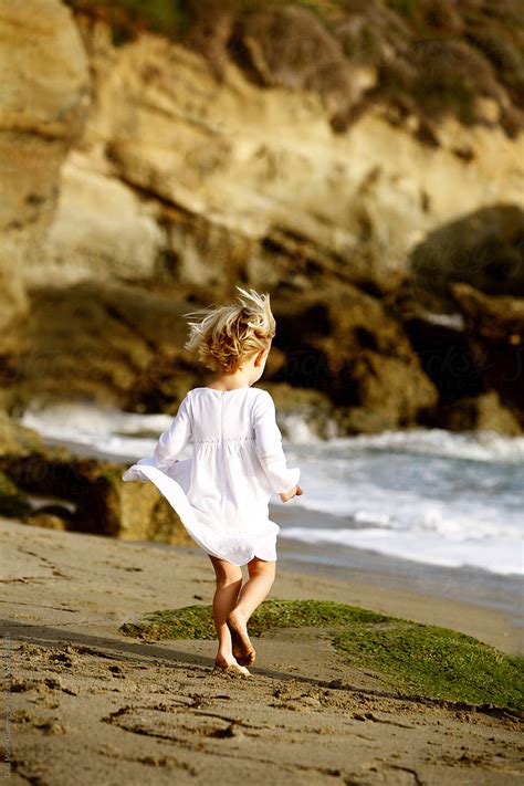 Little Girl Running On Beach With Dress And Hair In Motion By Stocksy