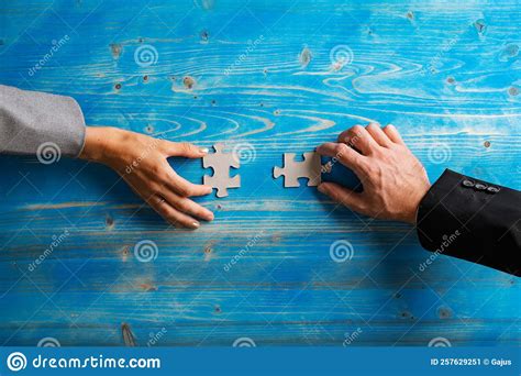 Hands Of Businesswoman And Businessman Holding Matching Puzzle Pieces