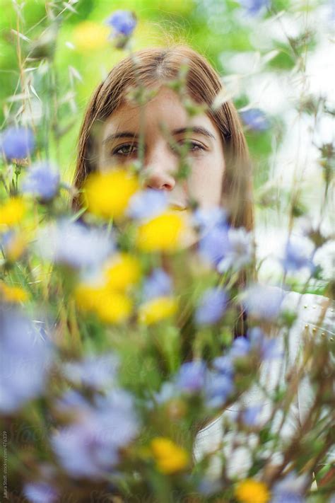 Springtime Queen Young Woman Looks At Camera Through Mixed Wildflowers Bouquet By Stocksy