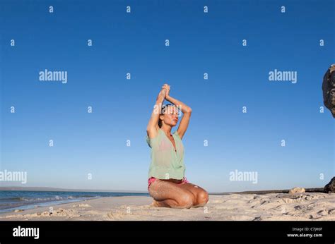 Rear View Of Sensuous Female Model Kneeling In Bikini At Beach High Res