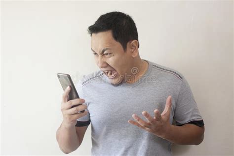 Young Man Getting Bad News On Phone Shocked And Angry Stock Image